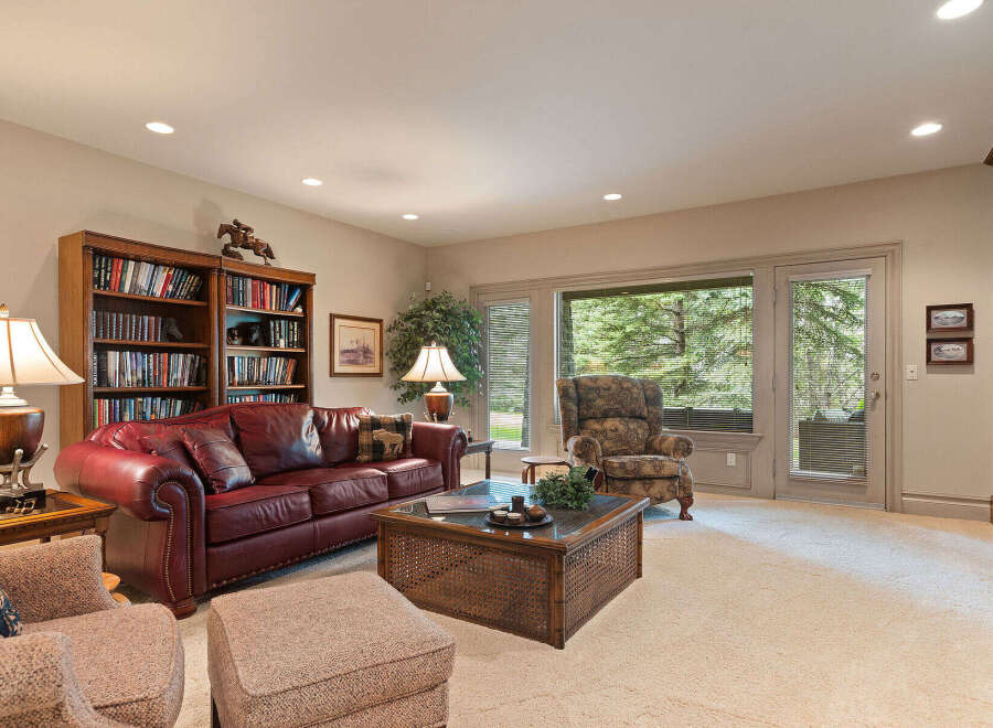 This inviting living room features a rich, burgundy leather sofa complemented by a plush armchair and ottoman, creating a cozy seating area.