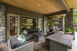 Enjoy outdoor living at its finest on this expansive covered patio, featuring a comfortable sectional sofa, a stylish coffee table, and a relaxing swing.