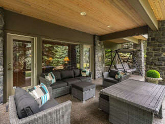 Enjoy outdoor living at its finest on this expansive covered patio, featuring a comfortable sectional sofa, a stylish coffee table, and a relaxing swing.