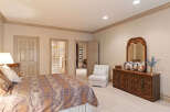 This spacious bedroom features a luxurious king-sized bed with an ornate comforter, complemented by a classic wooden dresser with a large mirror.
