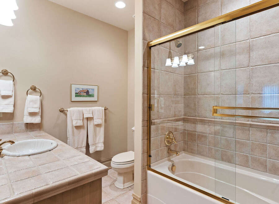This charming bathroom features a tiled countertop with a classic white sink and elegant brass fixtures.