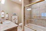 This charming bathroom features a tiled countertop with a classic white sink and elegant brass fixtures.