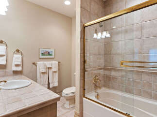 This charming bathroom features a tiled countertop with a classic white sink and elegant brass fixtures.