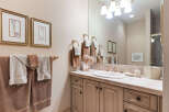 This elegant bathroom features a vanity with a tiled countertop and a large mirror, complemented by decorative framed artwork and plush towels.