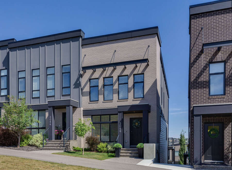 Discover modern townhome living with this stunning property featuring a sleek facade of gray vertical siding and light brick.