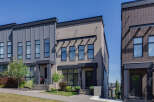 Discover modern townhome living with this stunning property featuring a sleek facade of gray vertical siding and light brick.