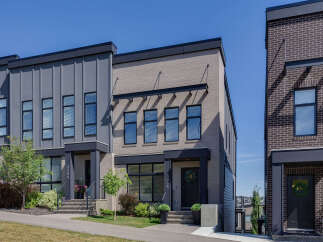 Discover modern townhome living with this stunning property featuring a sleek facade of gray vertical siding and light brick.