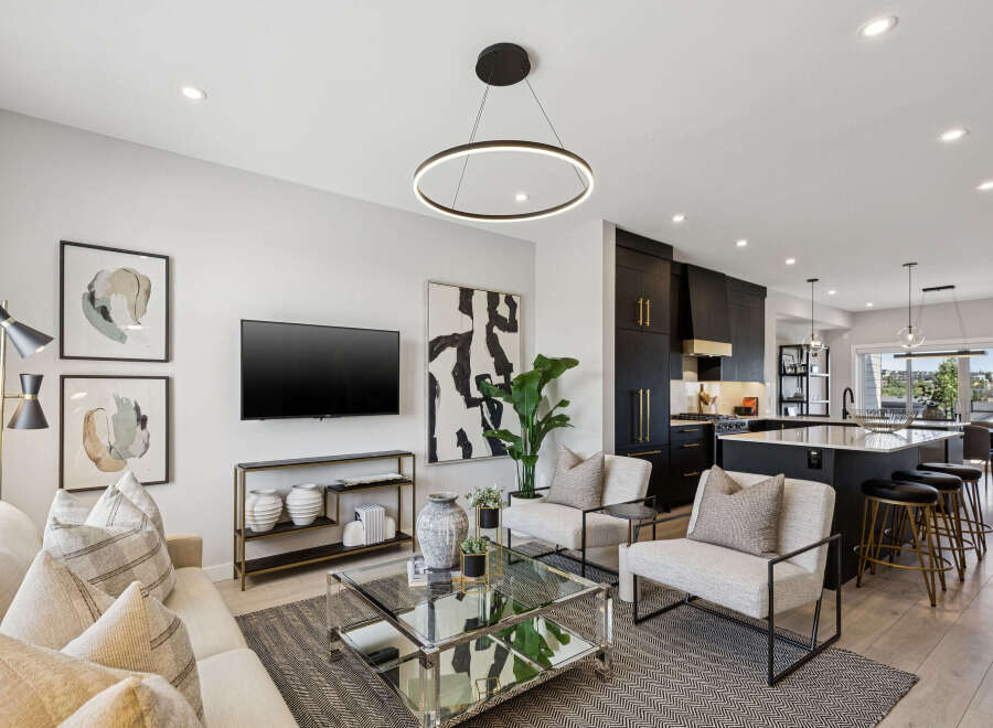 Experience modern living in this stunning open-concept space, featuring a sleek black kitchen with gold accents and a spacious island perfect for entertaining.