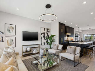 Experience modern living in this stunning open-concept space, featuring a sleek black kitchen with gold accents and a spacious island perfect for entertaining.