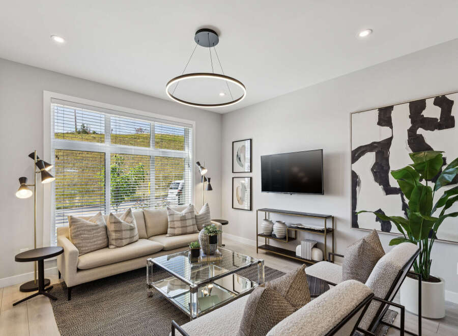Experience modern living in this stylish living room, featuring a comfortable sectional sofa adorned with decorative pillows and a sleek glass coffee table.