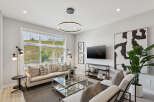Experience modern living in this stylish living room, featuring a comfortable sectional sofa adorned with decorative pillows and a sleek glass coffee table.