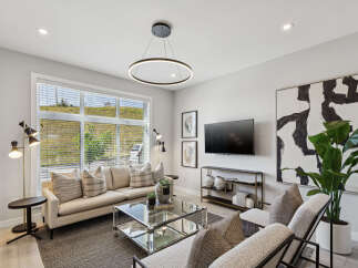 Experience modern living in this stylish living room, featuring a comfortable sectional sofa adorned with decorative pillows and a sleek glass coffee table.