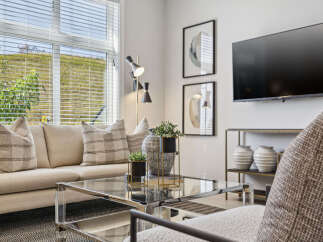 Experience modern living in this stylish living room, featuring a comfortable neutral-toned sofa adorned with plaid accent pillows.