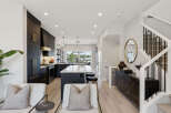 Experience modern luxury in this stunning kitchen and living area, featuring sleek dark cabinetry with elegant gold hardware and a spacious island perfect for entertaining.