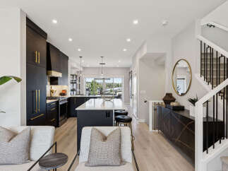 Experience modern luxury in this stunning kitchen and living area, featuring sleek dark cabinetry with elegant gold hardware and a spacious island perfect for entertaining.