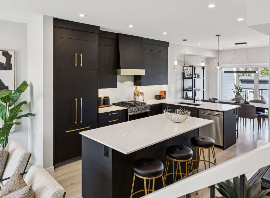 Experience modern luxury in this stunning kitchen featuring sleek black cabinetry with elegant gold hardware.