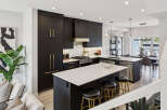 Experience modern luxury in this stunning kitchen featuring sleek black cabinetry with elegant gold hardware.