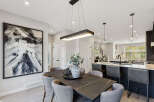 Experience modern living in this open-concept dining and kitchen area, featuring a sleek rectangular chandelier and a striking abstract artwork.