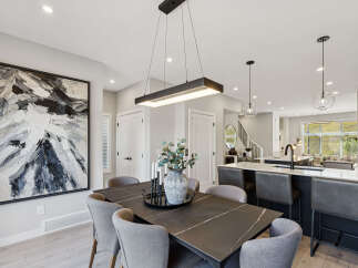 Experience modern living in this open-concept dining and kitchen area, featuring a sleek rectangular chandelier and a striking abstract artwork.