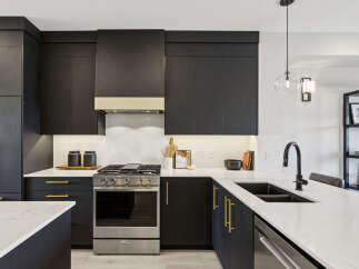 Experience modern luxury in this stunning kitchen, featuring sleek dark cabinetry complemented by elegant gold hardware.