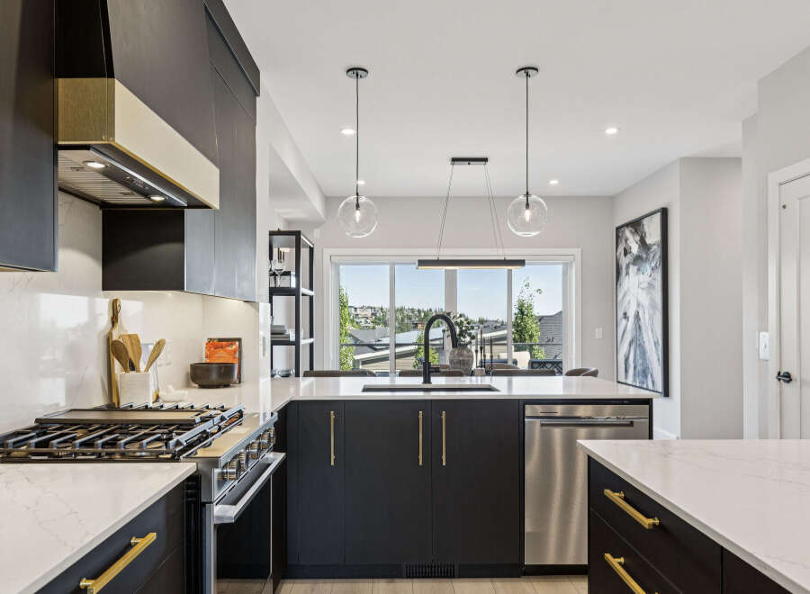 Experience modern luxury in this stunning kitchen, featuring sleek dark cabinetry with elegant gold hardware and a sophisticated marble-patterned countertop.