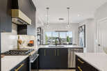 Experience modern luxury in this stunning kitchen, featuring sleek dark cabinetry with elegant gold hardware and a sophisticated marble-patterned countertop.