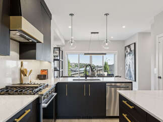 Experience modern luxury in this stunning kitchen, featuring sleek dark cabinetry with elegant gold hardware and a sophisticated marble-patterned countertop.