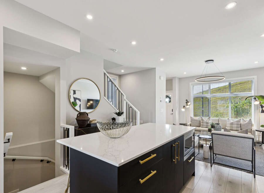 Experience modern living in this stunning open-concept home, featuring a sleek kitchen island with quartz countertops and gold accents.
