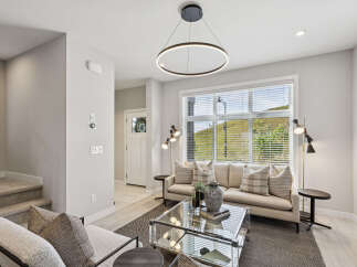 Step into this beautifully appointed living room, featuring a plush sofa adorned with tasteful throw pillows and a modern glass coffee table.