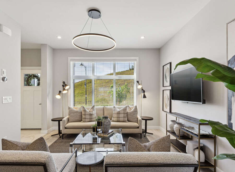 Experience modern living in this beautifully appointed living room, featuring a sleek circular pendant light and a large window offering scenic views.