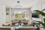 Experience modern living in this beautifully appointed living room, featuring a sleek circular pendant light and a large window offering scenic views.