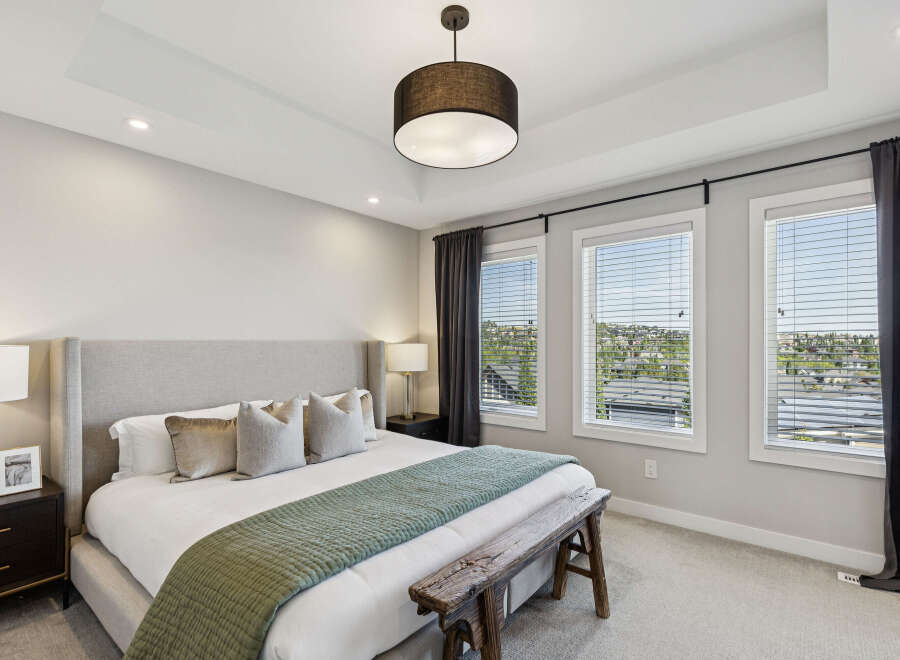 Experience luxury in this master bedroom, featuring a king-sized bed with a tall upholstered headboard and plush pillows.