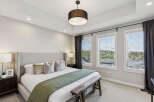 Experience luxury in this master bedroom, featuring a king-sized bed with a tall upholstered headboard and plush pillows.