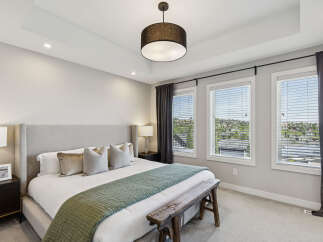 Experience luxury in this master bedroom, featuring a king-sized bed with a tall upholstered headboard and plush pillows.