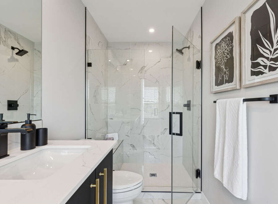Experience modern luxury in this stunning bathroom featuring a spacious glass-enclosed shower with marble tile and sleek black fixtures.