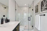 Experience modern luxury in this stunning bathroom featuring a spacious glass-enclosed shower with marble tile and sleek black fixtures.