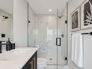 Experience modern luxury in this stunning bathroom featuring a spacious glass-enclosed shower with marble tile and sleek black fixtures.
