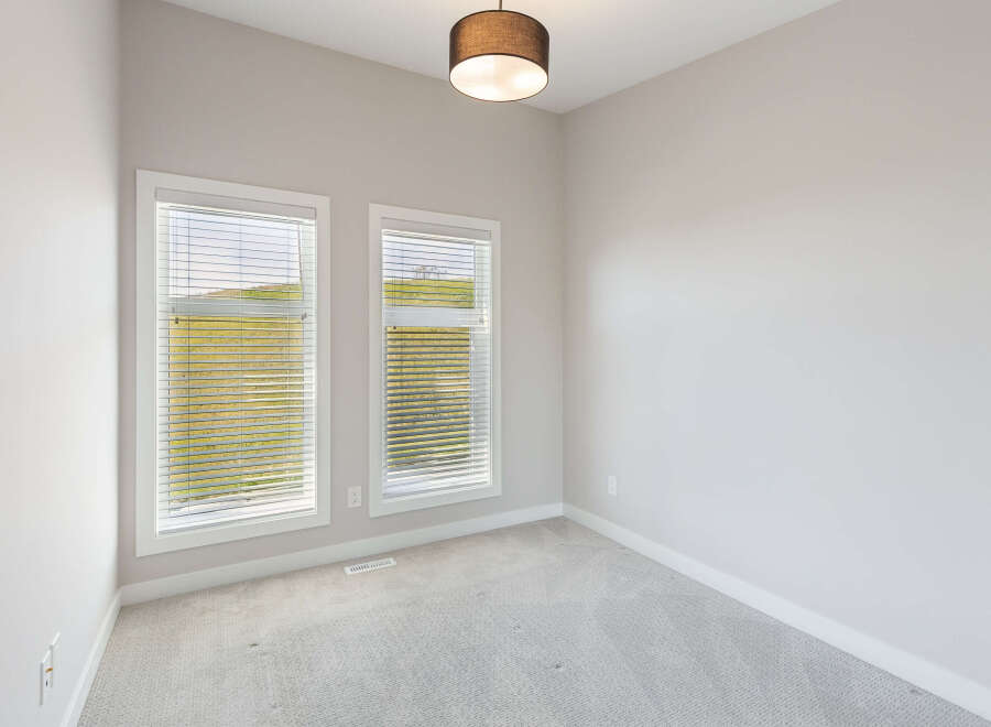 This bright and airy room features two large windows that flood the space with natural light, offering scenic views of the surrounding landscape.