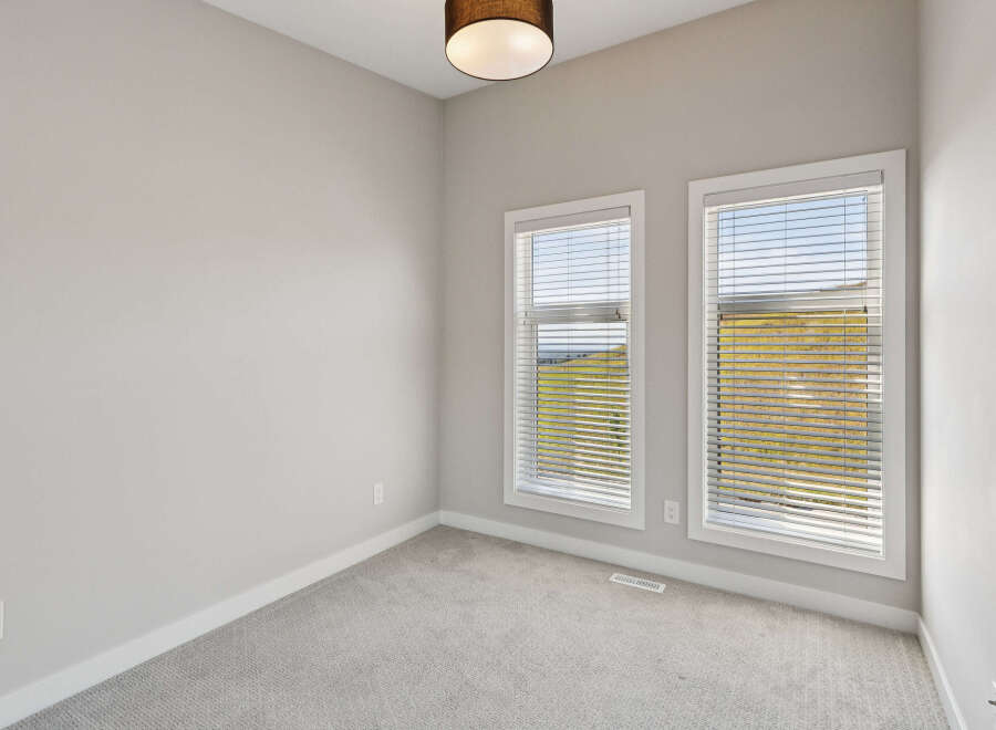 This empty room features neutral gray carpeting and walls, creating a blank canvas for your personal style.