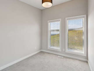 This empty room features neutral gray carpeting and walls, creating a blank canvas for your personal style.