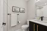 This modern bathroom features a sleek black vanity with gold hardware, complemented by a white quartz countertop and a matte black faucet.