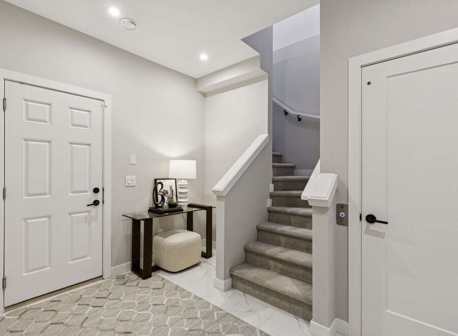 Step into this inviting entryway featuring a sleek glass console table with a decorative lamp and ottoman, perfect for adding a touch of style.