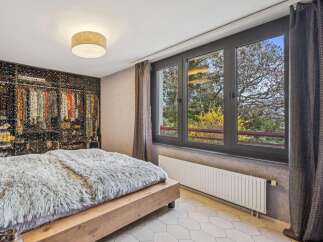 Experience modern comfort in this stylish bedroom featuring a plush, faux-fur throw on a wooden bed frame.