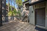 Step onto the charming wooden deck and ascend the stairs to this inviting entrance, nestled amongst mature trees.
