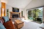 Experience breathtaking lake views from this stunning living room, featuring a cozy stone fireplace and a large sliding glass door that opens to a private deck.