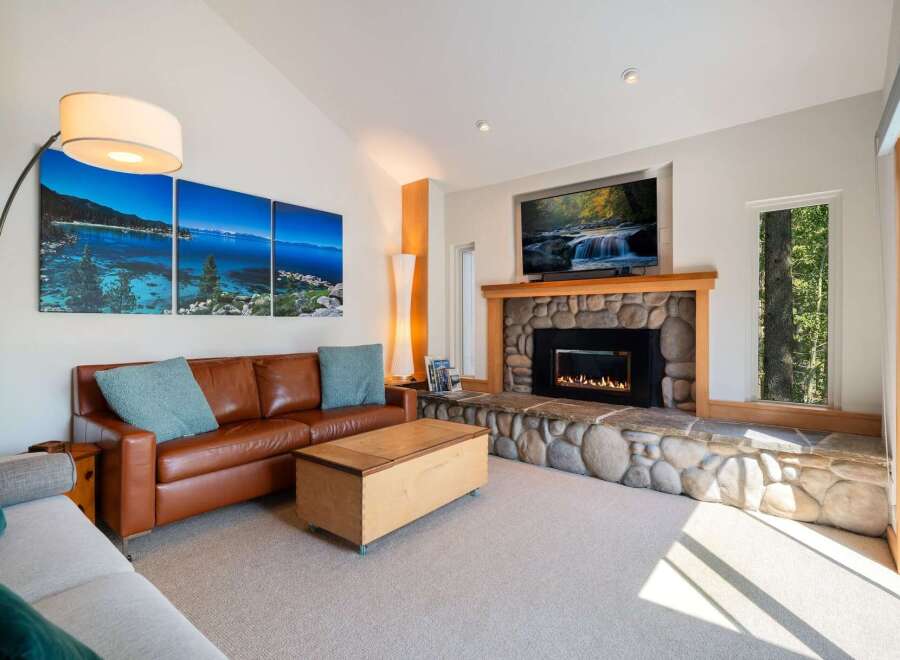 Experience luxury living in this stunning living room, featuring a cozy stone fireplace and a large flat-screen TV perfect for entertainment.