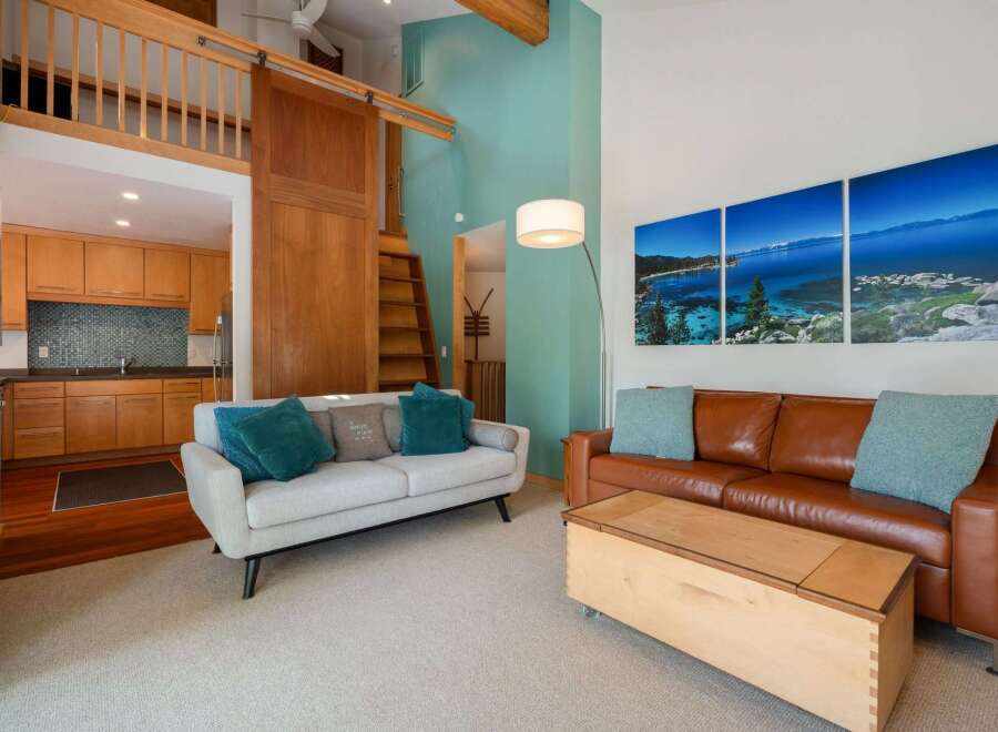 Experience modern living in this stunning loft-style apartment, featuring a spacious open-concept living area with a cozy sectional sofa and a rich leather couch.