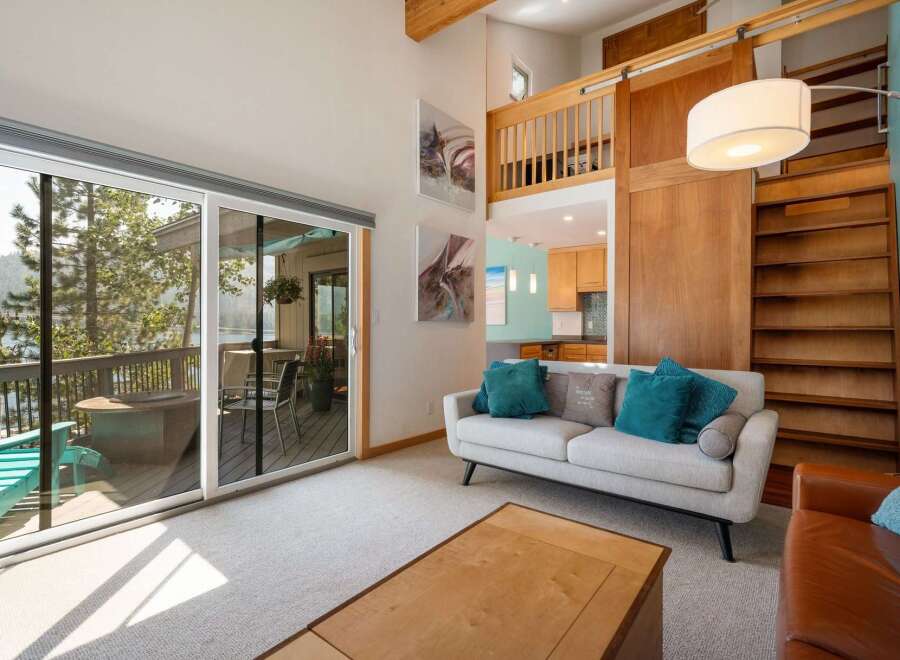 Experience breathtaking lake views from this stunning living room, featuring a spacious deck accessible through large sliding glass doors.