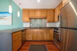 This modern kitchen features sleek, light wood cabinetry complemented by a stylish mosaic tile backsplash.