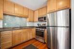 This modern kitchen features sleek, light wood cabinetry complemented by a striking mosaic tile backsplash.